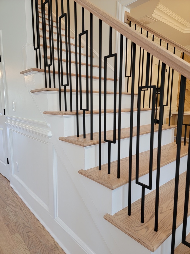 Modern stair remodel with oak treads, white risers, and a geometric matte black baluster design