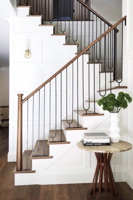 Modern staircase remodel with matte black metal balusters and a warm wood handrail
