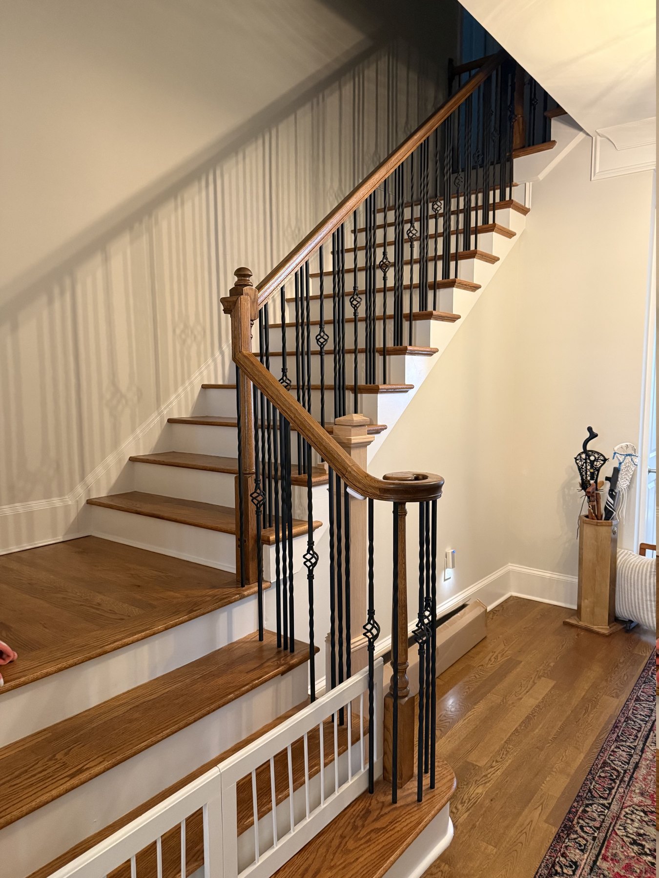 Alpharetta, GA staircase before remodeling &mdash; dark-stained oak treads, matching handrail and turned newel posts