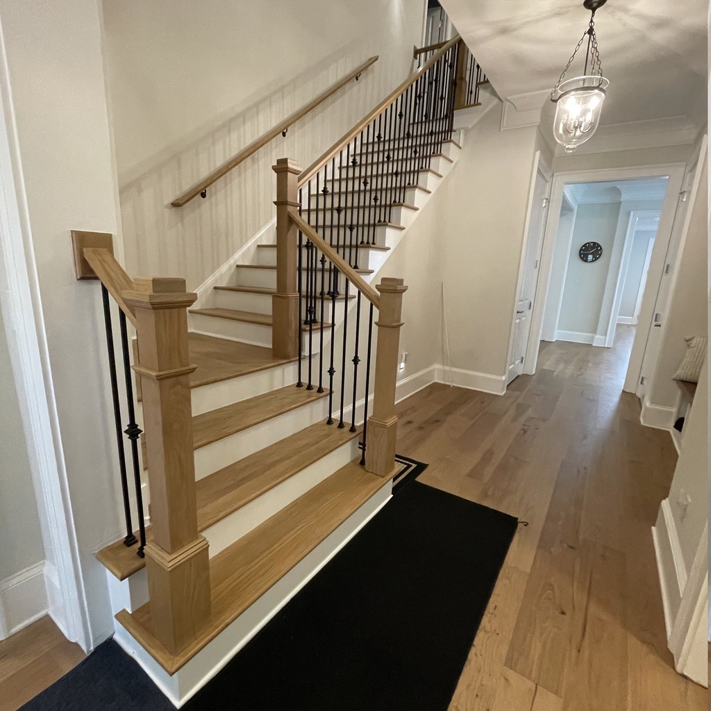 Remodeled staircase in an Alpharetta, GA home — white oak treads and handrail, painted risers and iron balusters, with new wide-plank white oak flooring