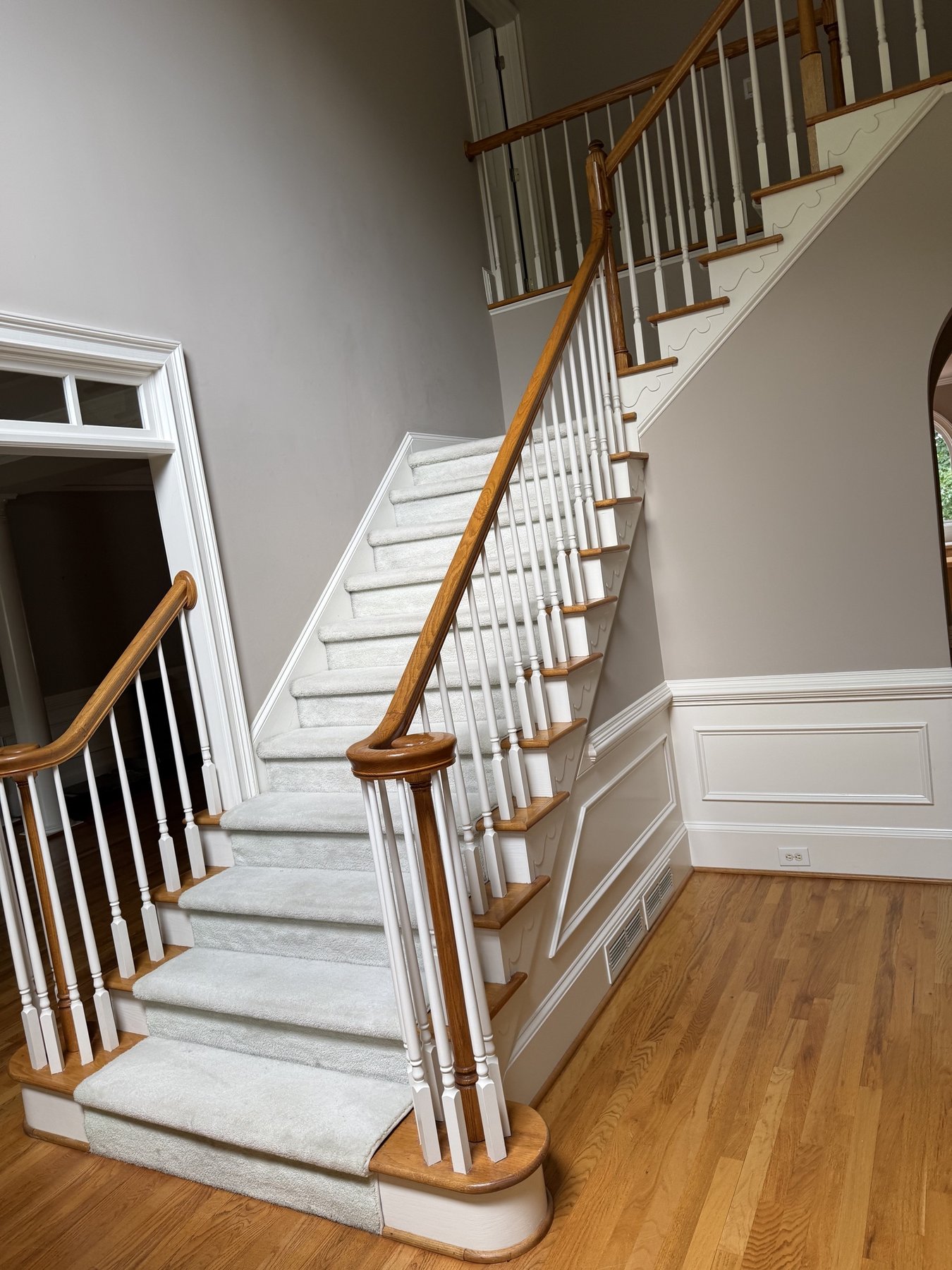 Alpharetta, GA staircase before remodeling &mdash; carpet runner over oak treads, thin white spindles and a turned oak handrail